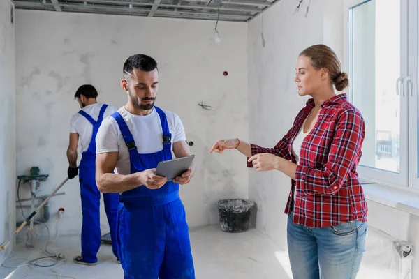 El cliente habla con el trabajador en overol. Escribe en un cuaderno — Foto de Stock