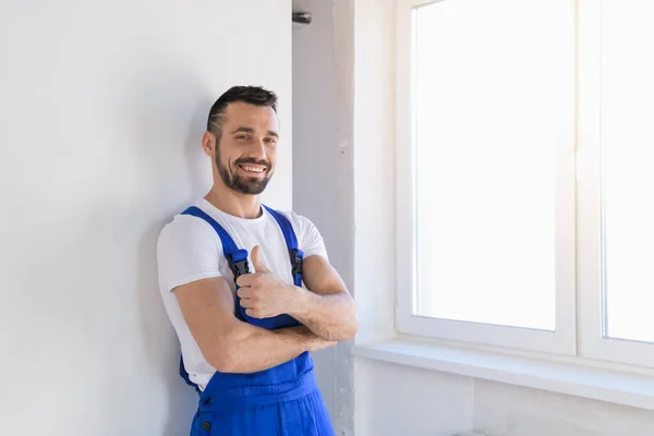 Constructeur en uniforme montrant pouce et sourire Photo De Stock