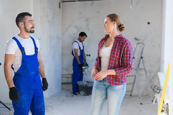 La mujer habla positivamente con el constructor sobre la renovación del apartamento Imagen de stock