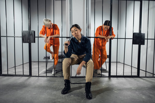 Asian womens prison. In the cell there are two young girls convicted of a criminal offense and a female warden in a guards uniform