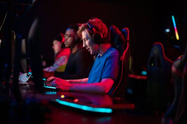 Uluslararası oyun etkinliği. Esport yarışmaları için arena. Kulaklıklı genç oyuncular popüler bir online oyun oynuyorlar.
