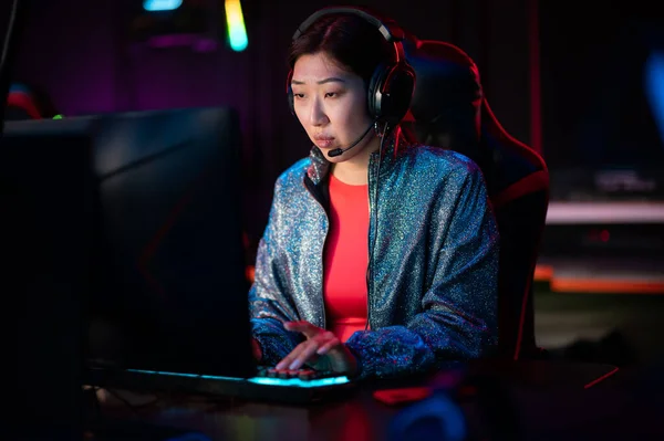 A young chinese esports player at an international esports tournament. A multi-racial cyber team is playing an online shooter game. Neon light. — Stock Photo, Image