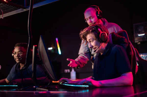During the Dota 2 tournament, two guys from the team play at the computers, the coach watches from behind — Stock Photo, Image