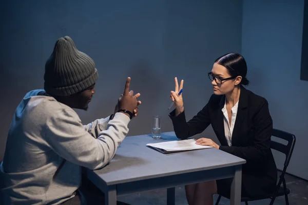 A black guy listens to his rights from a civil lawyer at a table in a visiting room in a state prison