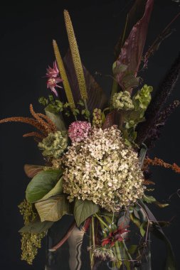 Beautiful bouquet of different flowers in vase on black background.