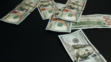 Siyah bir yüzeye düşen dolar banknotları