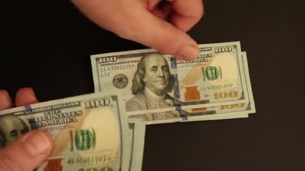 Ruce počítající dolary na černém povrchu