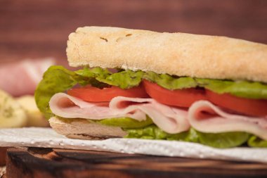 Jambonlu, domatesli ve marullu sandviçi kırsal bir arka planda bir tabakta yakın plan çek. Seçici odak.