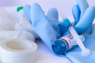 Boş tıbbi eldiven, pamuk, tıbbi bant, beyaz bir yüzeye şırınga ve aşı. Covid-19Aşı.