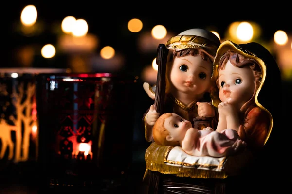 Christmas nativity scene with delicate figures recreating the Christian holiday. Classic Christmas scene lit by candles. Selective focus. Intimate light