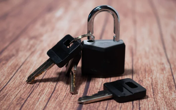 Very secure black padlock with keys on a wooden background. Concept of security and tranquility.