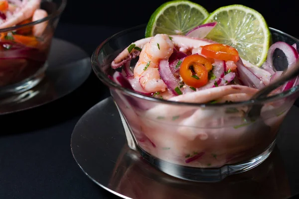 Tipik Peru yemeği, ceviche ile kalamar, karides ve beyaz balık ile mor soğan ve iyi bir kaplan sütü. Koyu arkaplanda cam bir konteynırda servis edilmiş. Gurme konsepti, zarafet