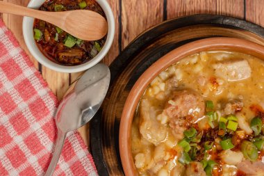 Tipik Arjantin mutfağı Locro ile seramik kase ve ahşap bir masada bu yahniye eşlik eden baharatlı sos. 25 Mayıs ve 9 Temmuz kutlamalarının geleneksel yemeği. Yakın çekim, hava görüntüsü.