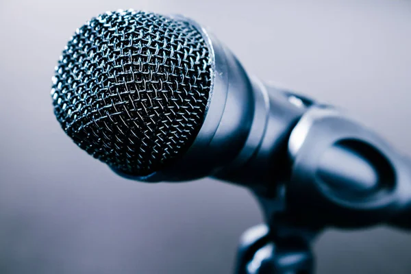 Small black desk microphone with cable and low stand on a black table. Modern style, Communication concept. Close-up.