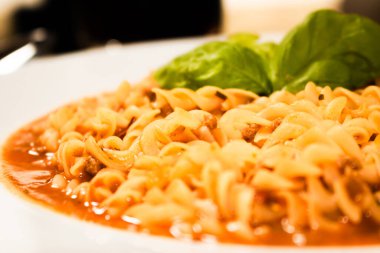 Domates soslu ve fesleğenli makarna. Yakın plan seçici odaklanma. 45 deg. görünüm