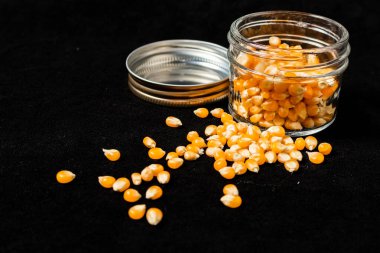 Siyah bir yüzey üzerinde cam bir kavanozda portakal tohumları. 45 deg. görünüm