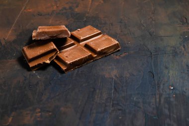 Koyu ve endüstriyel bir yüzeyde siyah çikolata parçaları..
