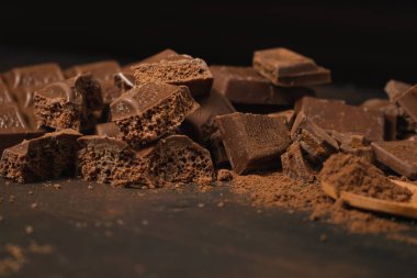 Koyu bir yüzeyde farklı siyah çikolata ve kakao tozları..