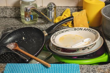 Kirli bulaşıklar, çatal bıçak takımı ve tavalar yıkanmaya hazır..