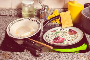 Kirli bulaşıklar, çatal bıçak takımı ve tavalar yıkanmaya hazır..