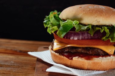 Marul, domates, kırmızı soğan ve domuz pastırmalı lezzetli hamburgerler tohumlu ev yapımı ekmek ve ahşap bir yüzeyde ketçap..