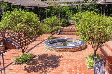 Güzel ve geleneksel Endülüs verandası ortasında bir çeşme, çeşmeyi çevreleyen portakal ağaçları, fayanslı koltuklar ve yan koridorları kaplayan bitkilerle dolu bir çardak..