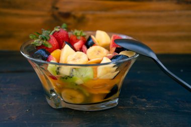 Doğal ve sağlıklı meyve salatası, şeffaf cam bir kâse içinde portakal seti, kırsal siyah bir yüzey üzerinde. Sağlıklı Gıda Konsepti, Sağlıklı Yaşam. 45 derecelik görünüm, yazma alanı