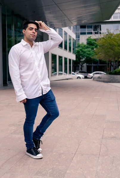 Full body portrait of a young Hispanic or Latino man at the entrance of a building. Modern Urban Concept.