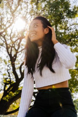 Güzel, mutlu, genç bir Latin kadının portresi. Sırtında güneş olan ışığa karşı. Sonbahar güneşi sabahları.