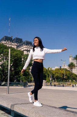 Siyah kot ve beyaz bluzuyla meydanda dans edip zıplayan genç, güzel siyah saçlı bir kadın..