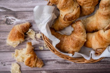 Bir tavada kruvasan veya ekmek sepetinde kruvasan parçaları ve ekmek kırıntıları masanın üzerinde..