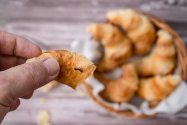 Adam ekmek sepetinden bir parça kruvasan alıyor..