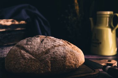 Ev yapımı ekmek kesme tahtasının üzerinde en son bıçakla ve ev ortamında yenir. Aydınlatma ana nesne olarak ekmeği vurguluyor.