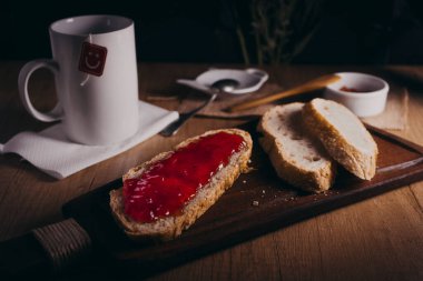 Masada ev yapımı ekmek dilimleri. Dilimlerden birinde domates reçeli var, ayrıca bir fincan çay da var..