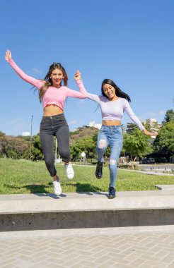 İki güzel genç kadın şehirde zıplıyor ve dans ediyor.