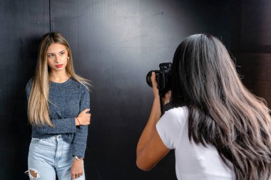 Bir mankenin yatay portresi ve fotoğraf stüdyosunda bir kadın fotoğrafçı, siyah arkaplan..