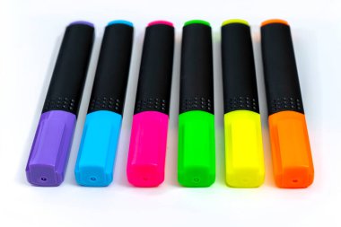 Beyaz arkaplandaki renklere göre sıralanmış fosforlu kalemler kümesi.