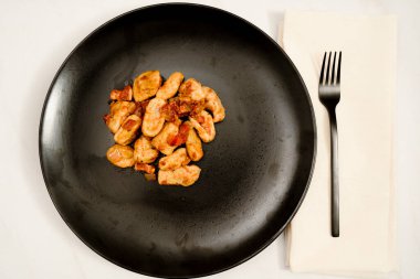 Beyaz mermer bir masada kırmızı soslu siyah Gnocchi tabağı. Modern siyah bir çatala eşlik ediyor. İtalyan Yemekleri