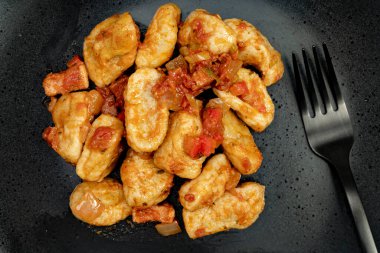 Siyah tabakta kırmızı sosla yakın plan Gnocchi görüntüsü. Modern siyah bir çatala eşlik ediyor. İtalyan yemeği.