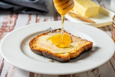 Sağlıklı bir kahvaltı hazırlıyorum tereyağlı bir tost ve arılardan elde edilen saf organik bal ile. Sağlıklı gıda konsepti.
