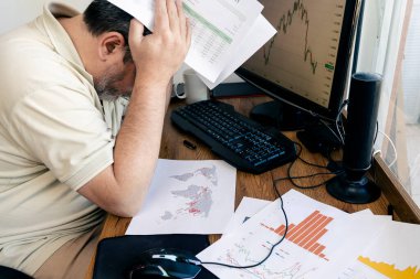 Kafkasyalı bir adam, elinde ve masasında yazılı hesap tabloları olan küresel ekonomik kayıplar hakkında endişeleniyor. konsept küreselleşme, ekonomi, hüsran, öfke, endişe.