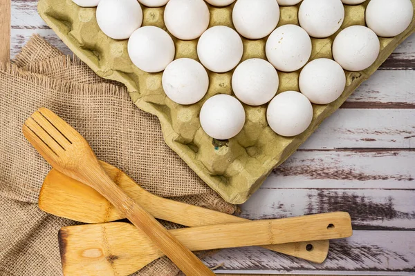 Aerial view of an egg carton container with organic white chicken eggs on a rustic wooden countertop. Farm Product.
