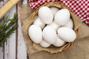 Biberiyeli ahşap bir masada sepetteki organik çiftlik beyaz yumurtalarının yukarıdan görünüşü. Çiftlik üretimi.