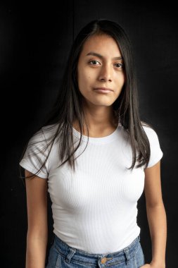 Medium vertical portrait of a beautiful Latin woman with black hair and a white T-shirt.