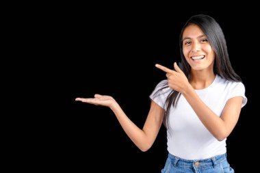 Beautiful Latin woman on black background with her outstretched hand holding imaginary and the other hand pointing to the imaginary held item.