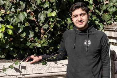 Çekici gülümseyen genç Latin adam beton parmaklıklara yaslanıyor..