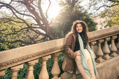 Güzel, genç ve zarif, kıvırcık saçlı, eski bir merdivenin beton parmaklıklarına dayanan İspanyol kadın..