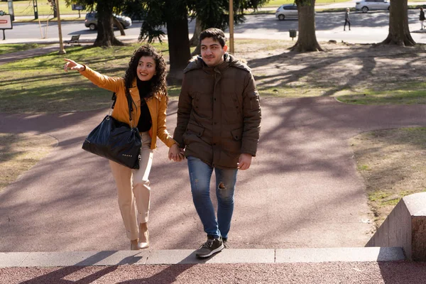 公園を歩きながら話している若いカップルの笑顔 人間関係の概念 — ストック写真