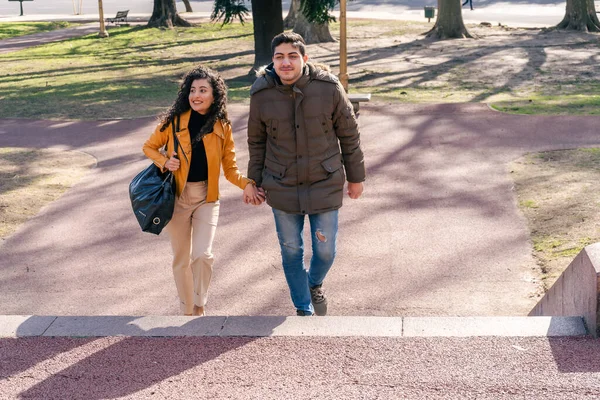 公園を歩きながら話している若いカップルの笑顔 人間関係の概念 — ストック写真