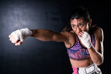 Genç Latin kadın boks ve kickboks yapıyor. Yumruğuyla direk yumruk atıyor. Diferansiyel odaklanma. Spor, spor, eğitim konsepti.